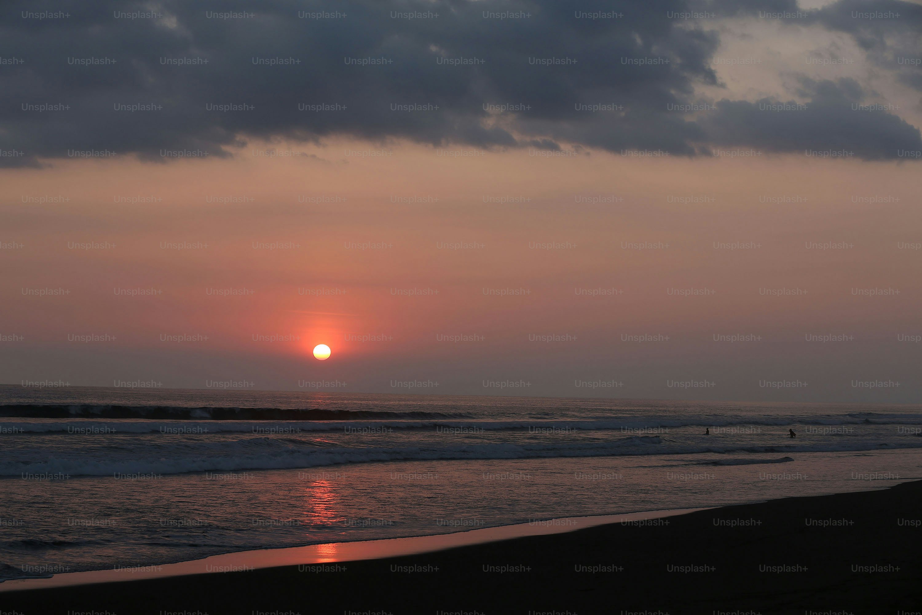 the sun is setting over the ocean on a cloudy day