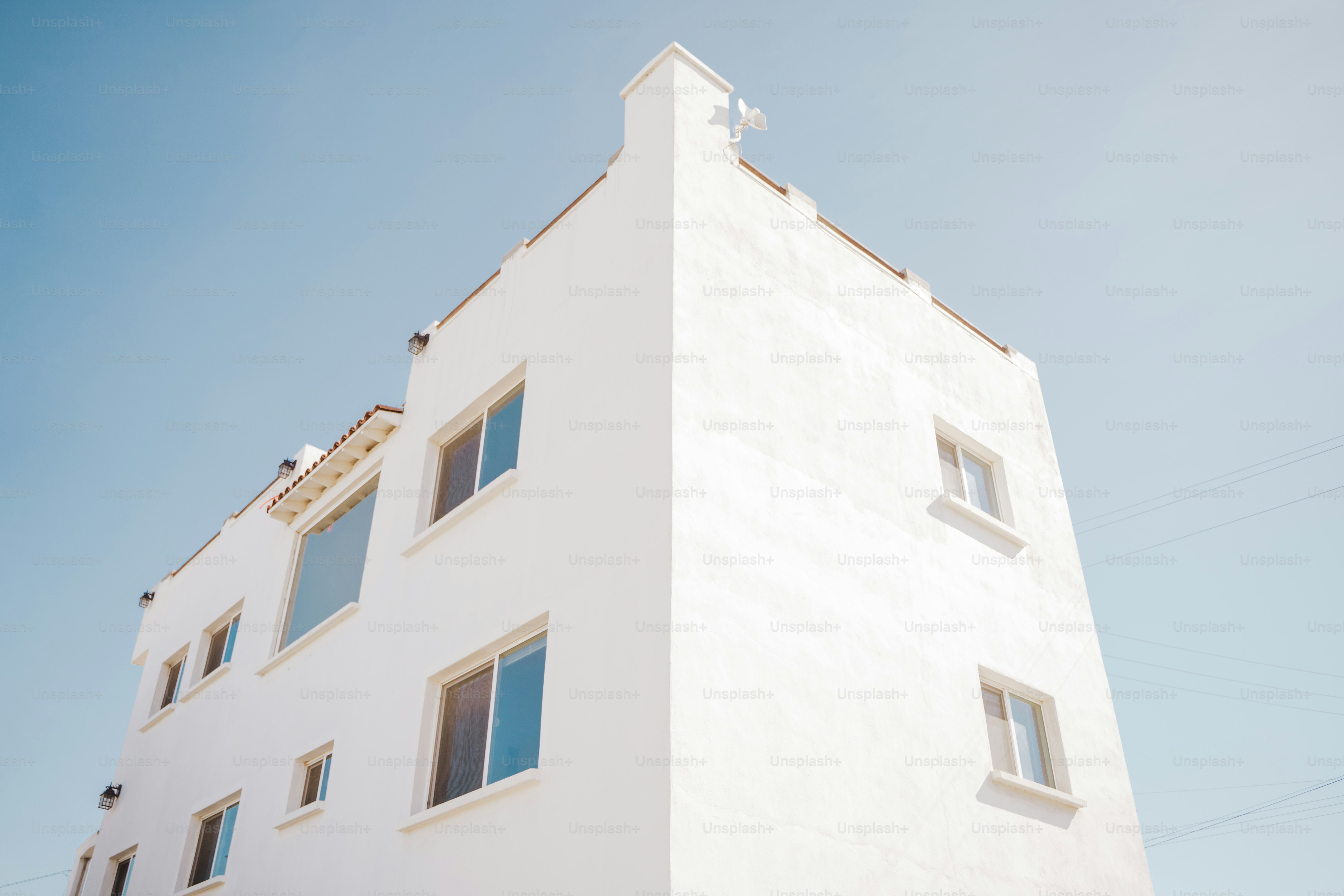 a tall white building with windows and a sky background