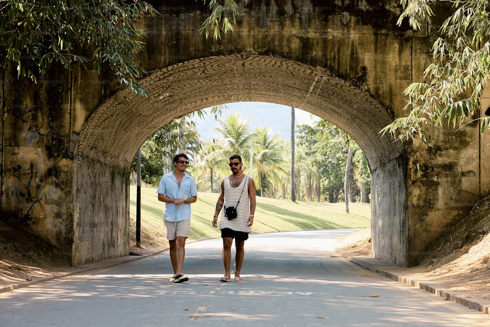 um casal de pessoas que estão andando sob uma ponte