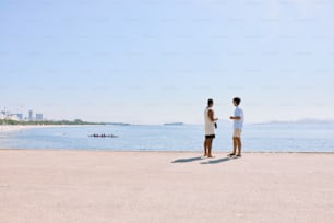 um casal de homens em pé um ao lado do outro em uma praia