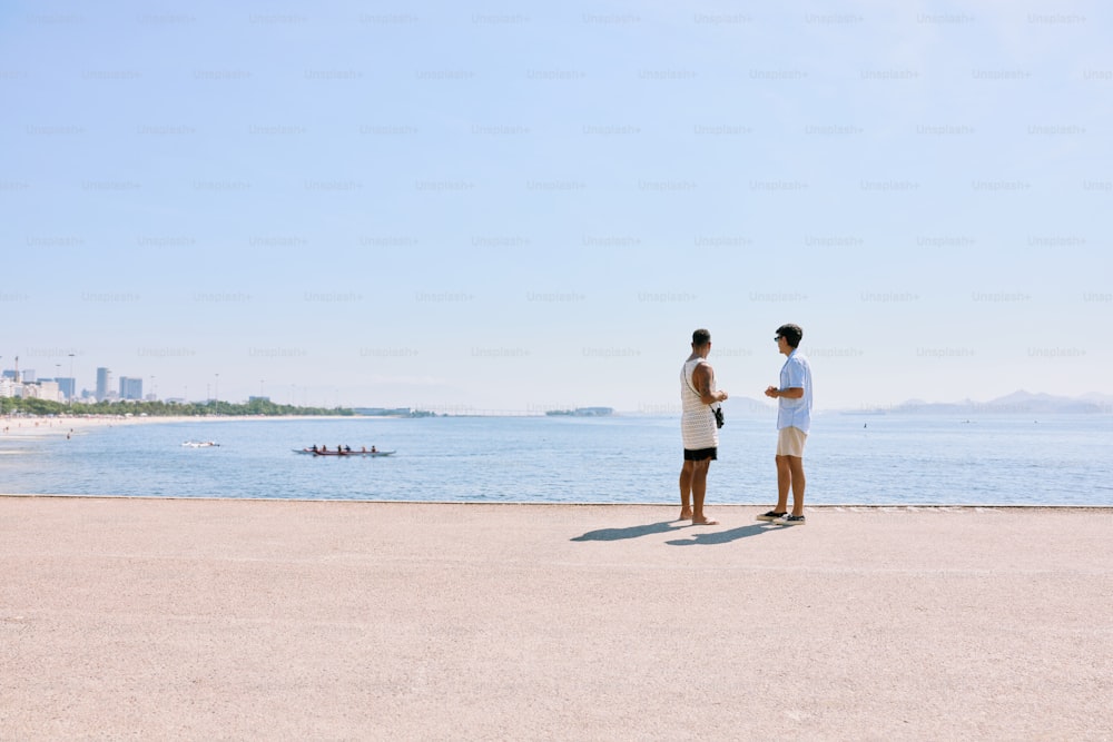 a couple of men standing next to each other on a beach