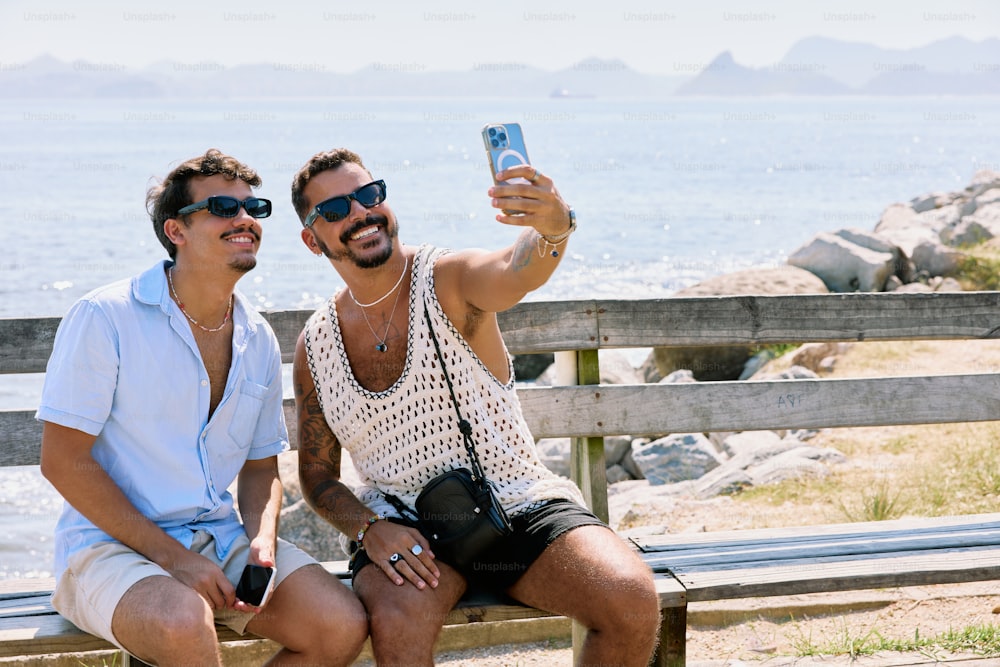 two men sitting on a bench taking a selfie