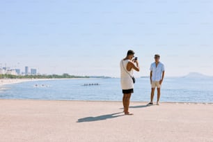 um homem tirando uma foto de uma mulher na praia