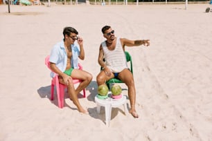 Dos hombres sentados en sillas de jardín en una playa