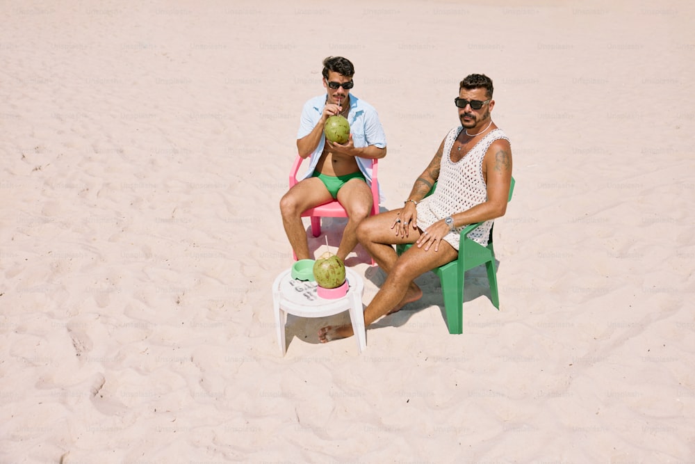 two men sitting in lawn chairs on a beach
