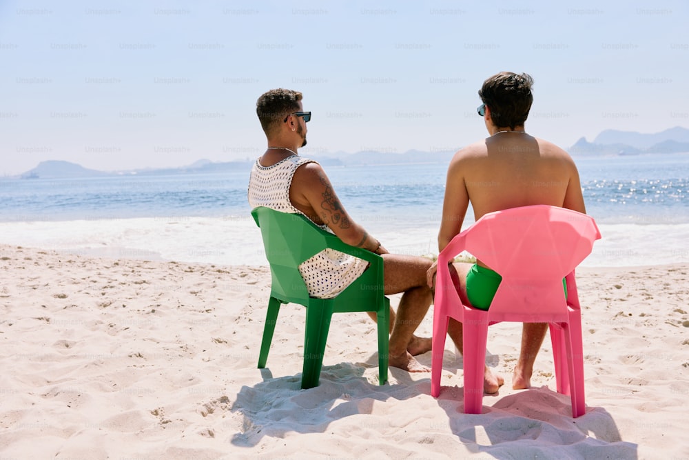 a couple of men sitting on top of green and pink chairs