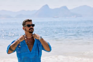 a man in a blue shirt and sunglasses on the beach