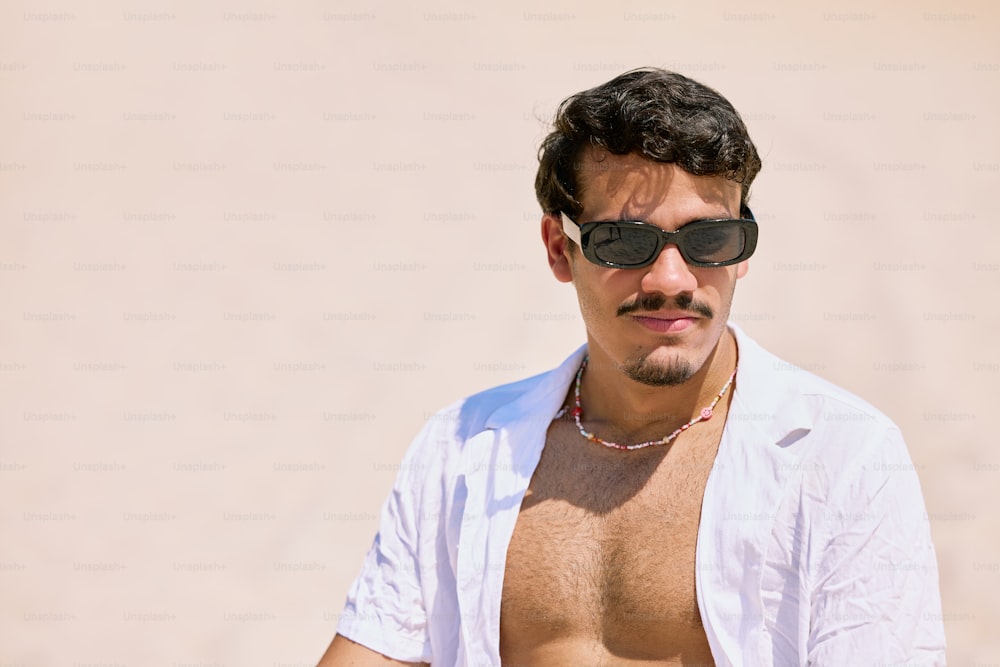 Un hombre sin camisa con gafas de sol y un collar