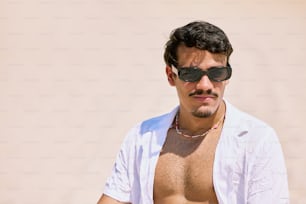 a shirtless man wearing sunglasses and a necklace