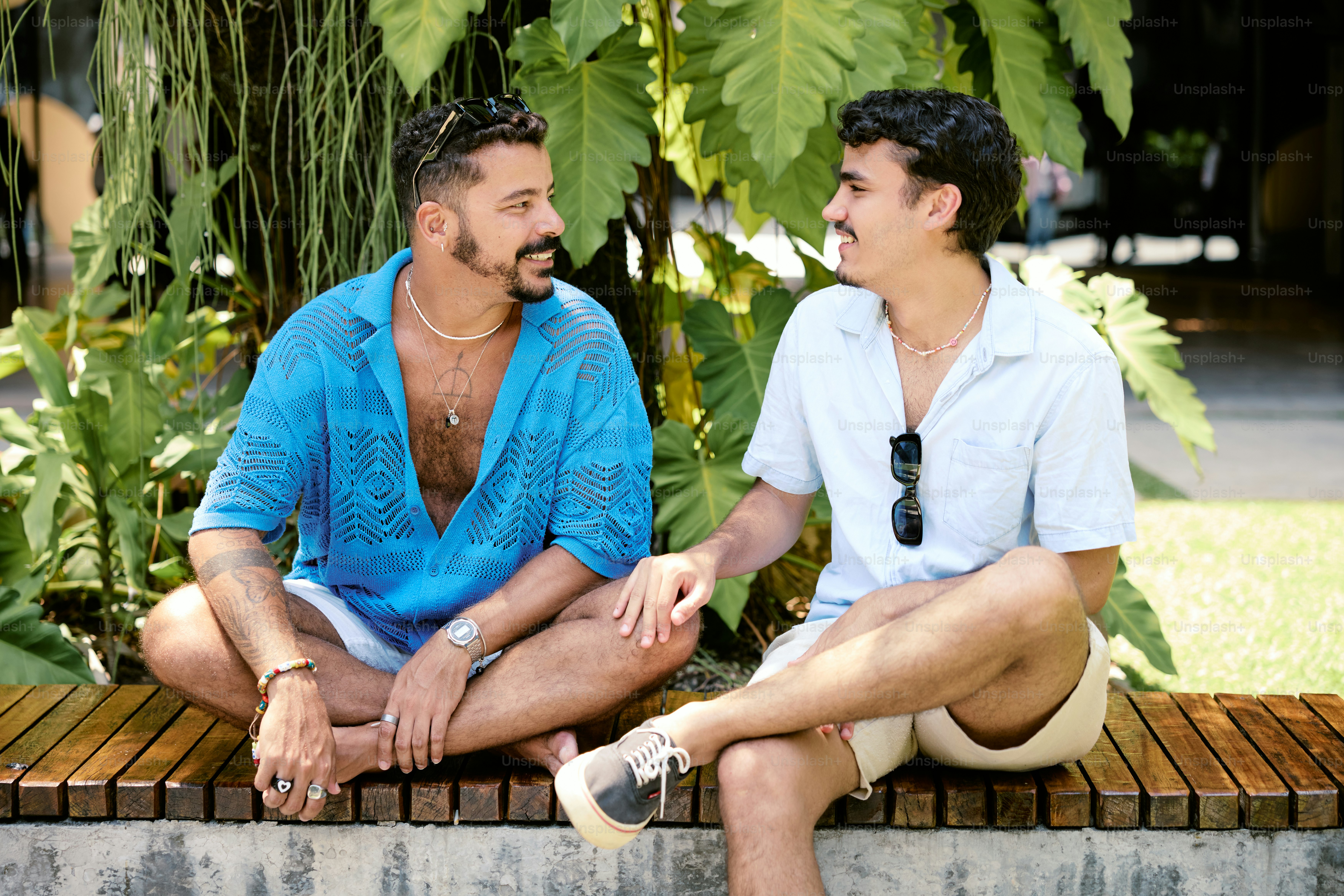 a couple of men sitting on top of a wooden bench