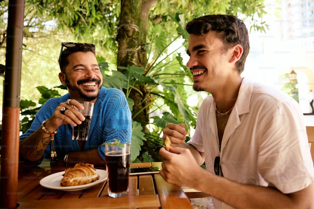 a couple of men sitting at a table with food