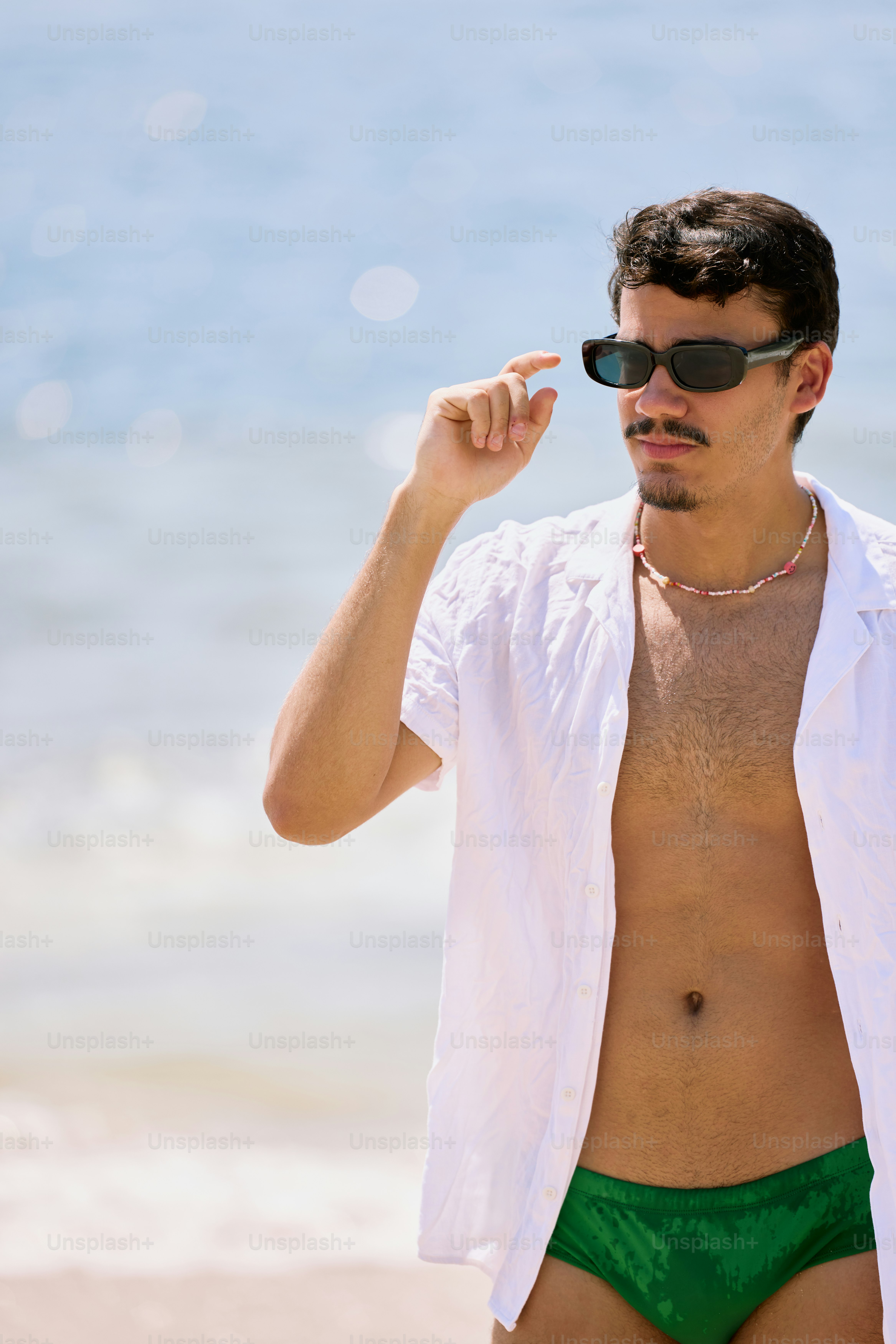 a man in a white shirt and green underwear on the beach