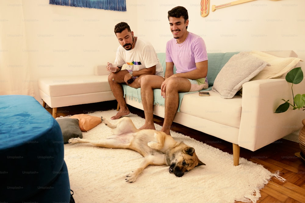 zwei Männer sitzen mit einem Hund auf einer Couch