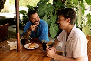 a couple of men sitting at a wooden table