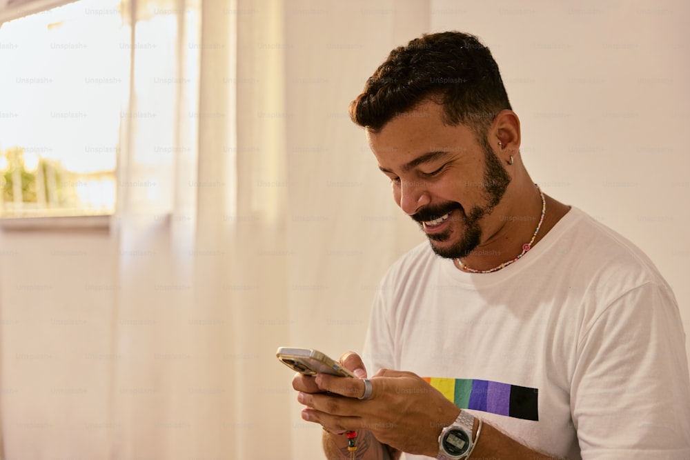 a man in a white t - shirt looking at his cell phone