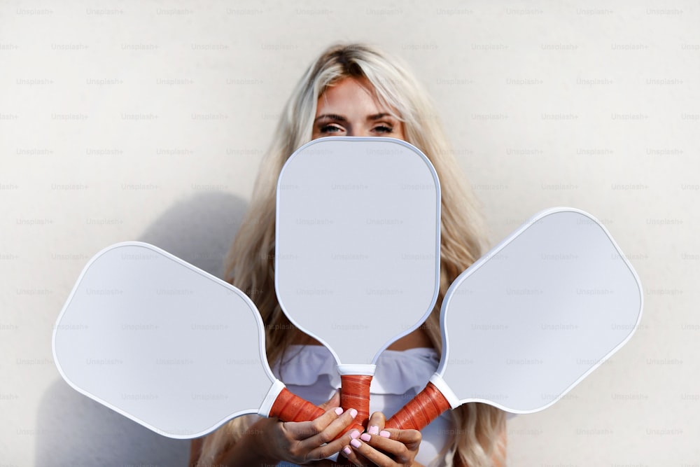 a woman holding up two large mirrors to her face
