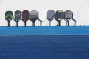 a row of tennis racquets sitting on top of a blue tennis court