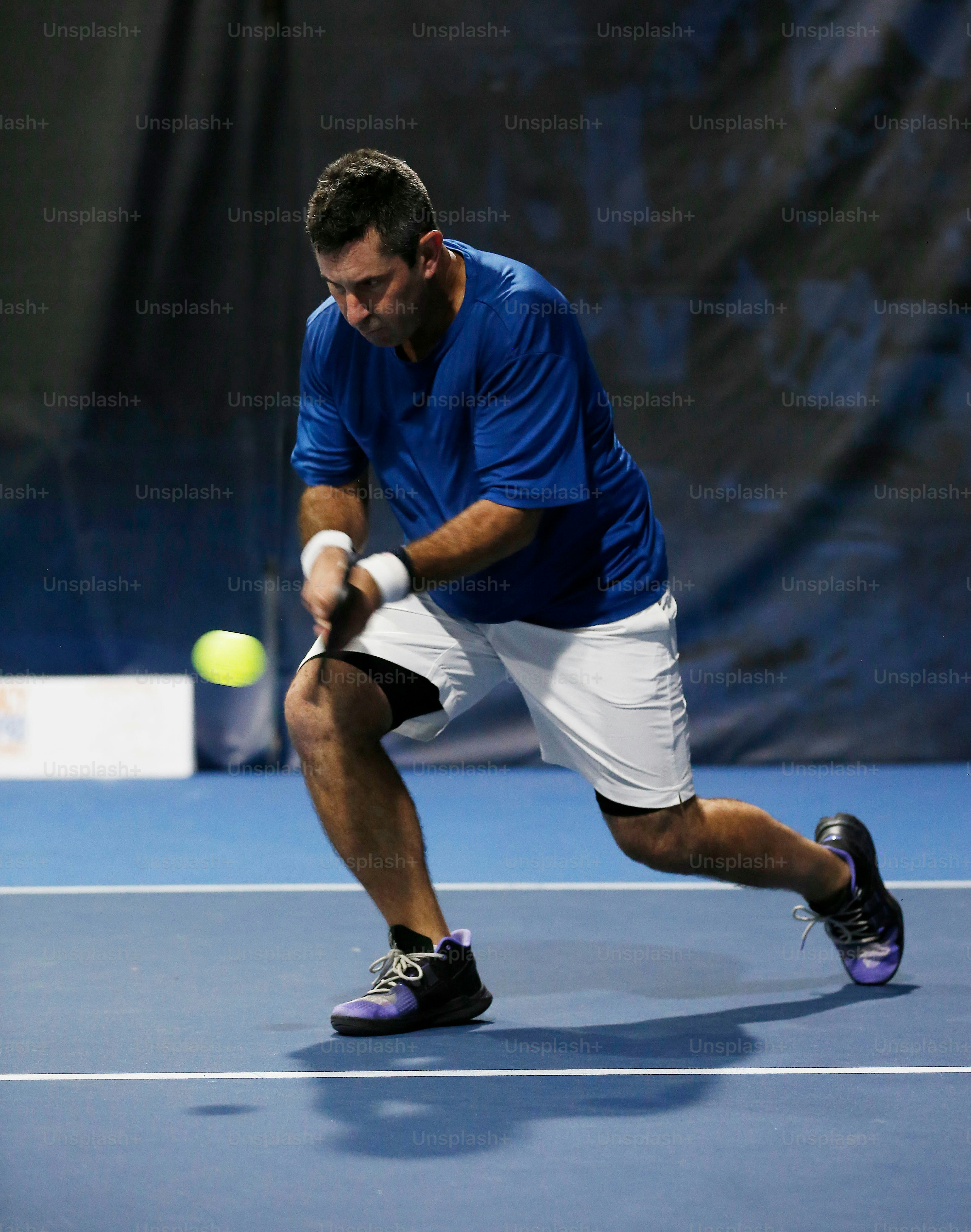 a man in blue shirt and white shorts playing a game of tennis