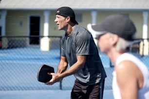 Un homme tenant un chapeau debout sur un court de tennis