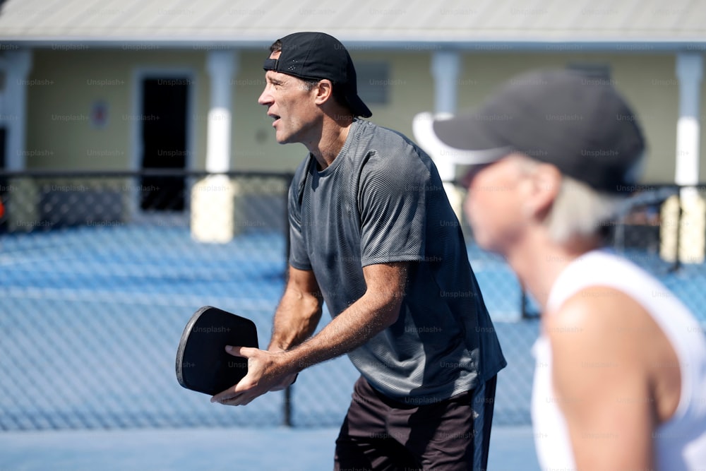 um homem segurando um chapéu enquanto estava em pé em uma quadra de tênis