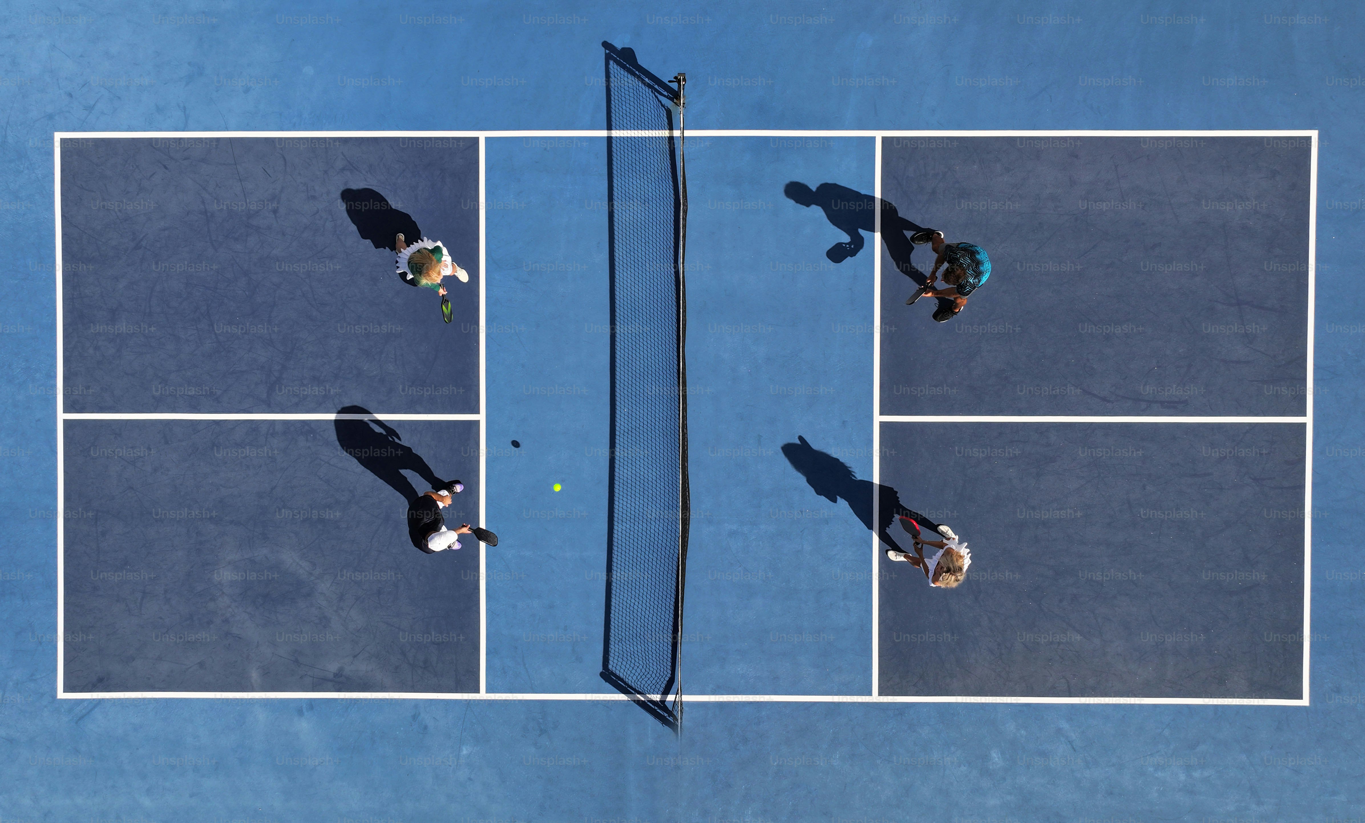 three people standing on a tennis court holding racquets