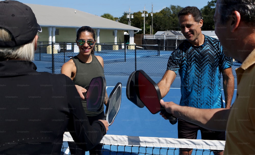 a group of people standing on a tennis court holding racquets