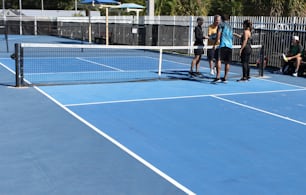 a group of people standing on top of a tennis court