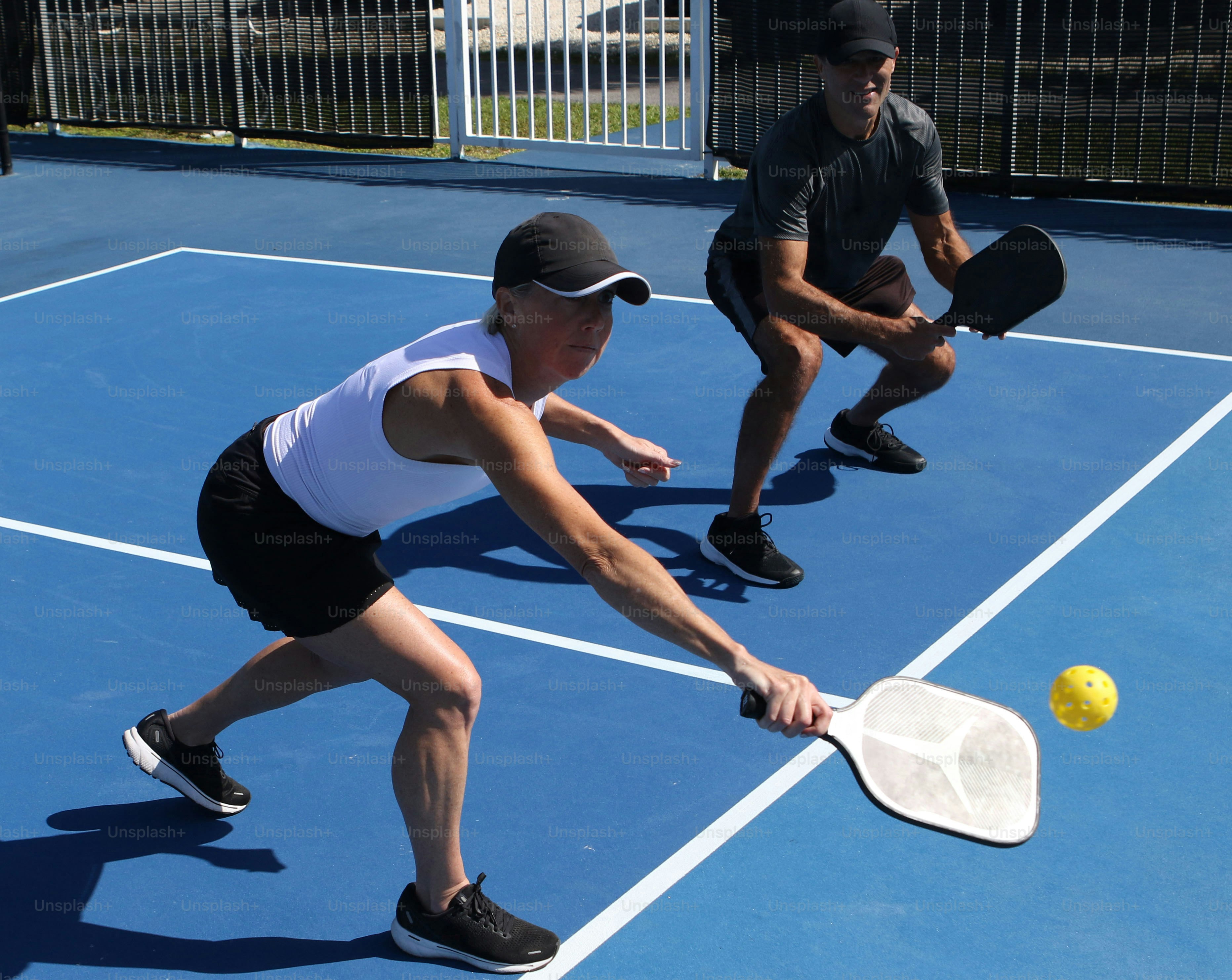 un uomo e una donna che giocano a tennis su un campo blu