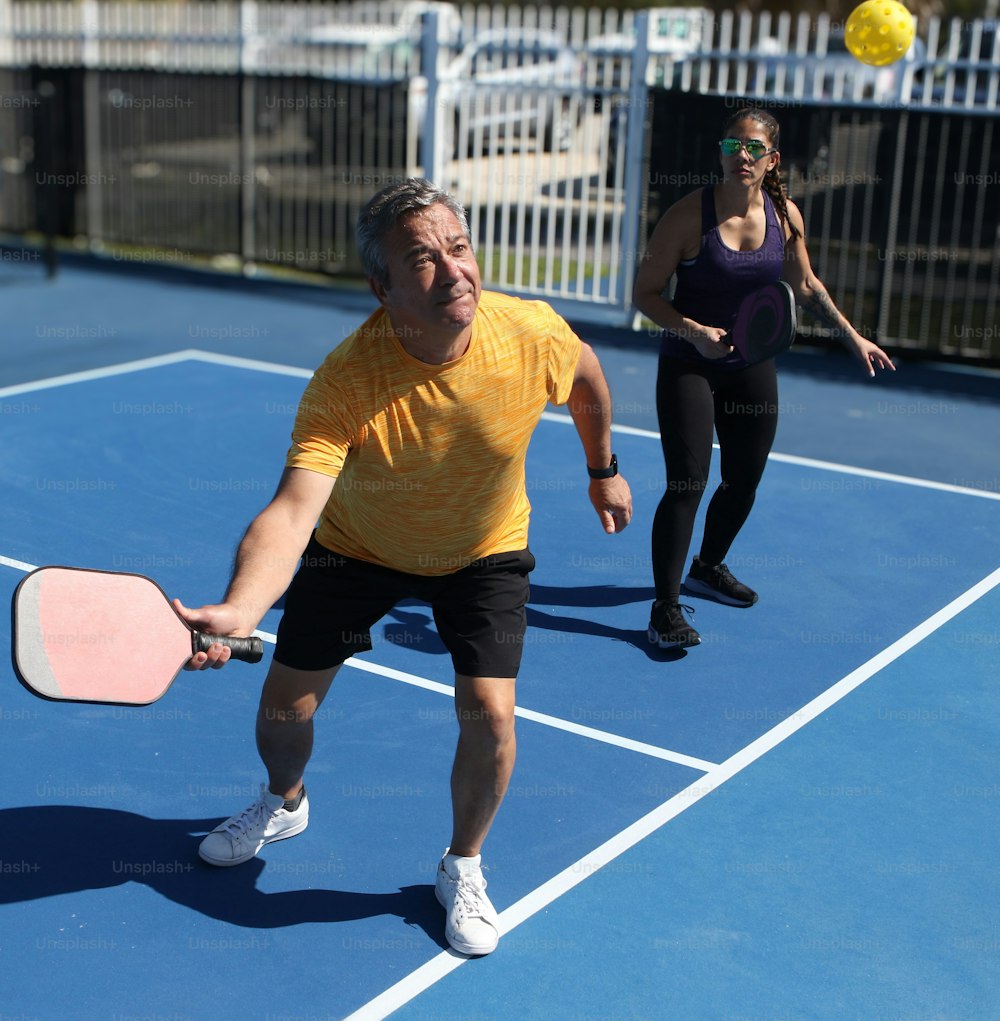 a man holding a pickleball racquet on top of a tennis court