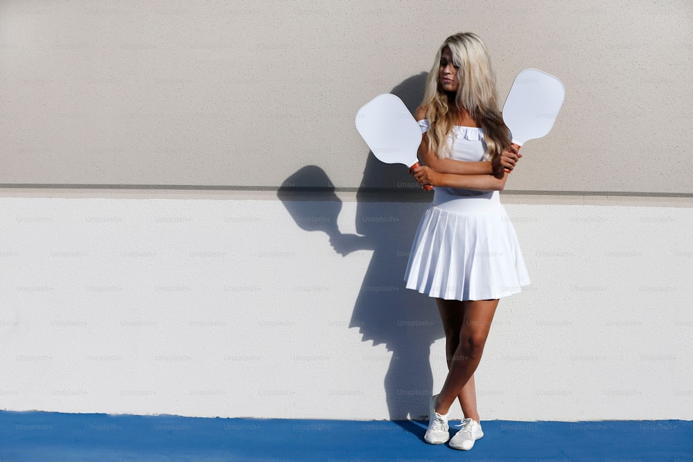 a woman in a white dress is holding a fan