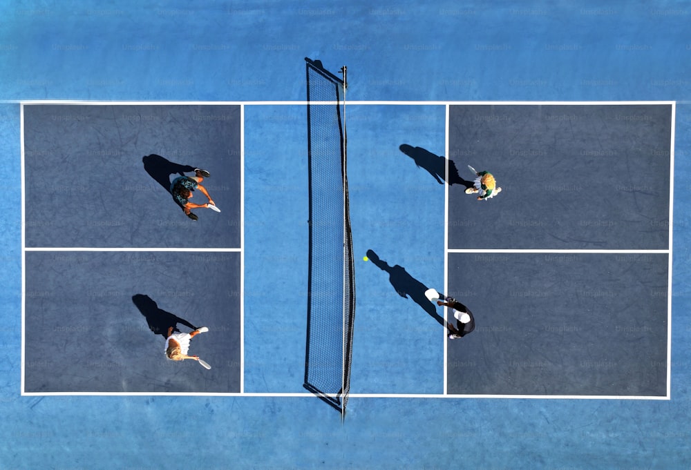 three people playing tennis on a blue tennis court