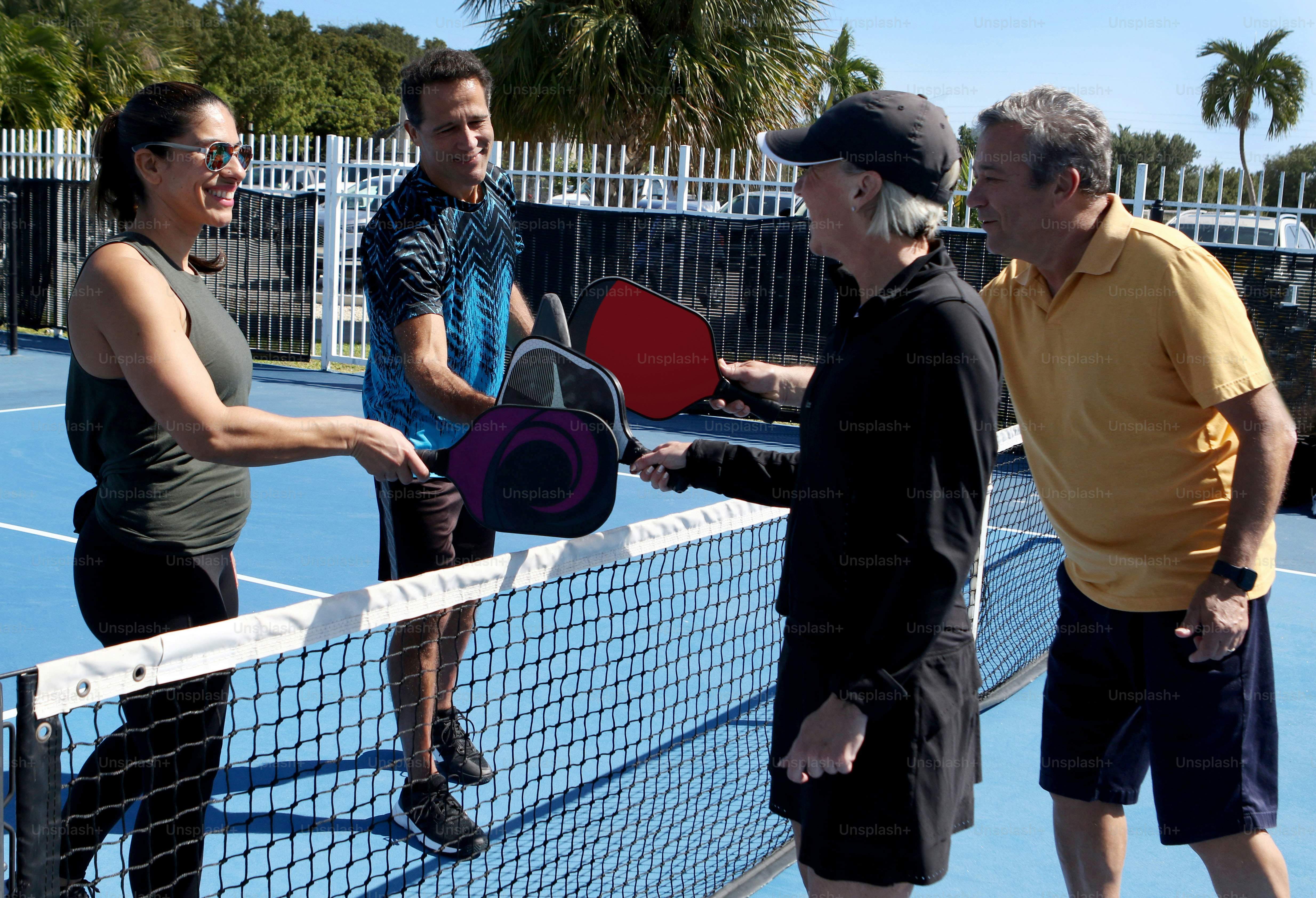 un gruppo di persone in piedi su un campo da tennis che tiene racchette