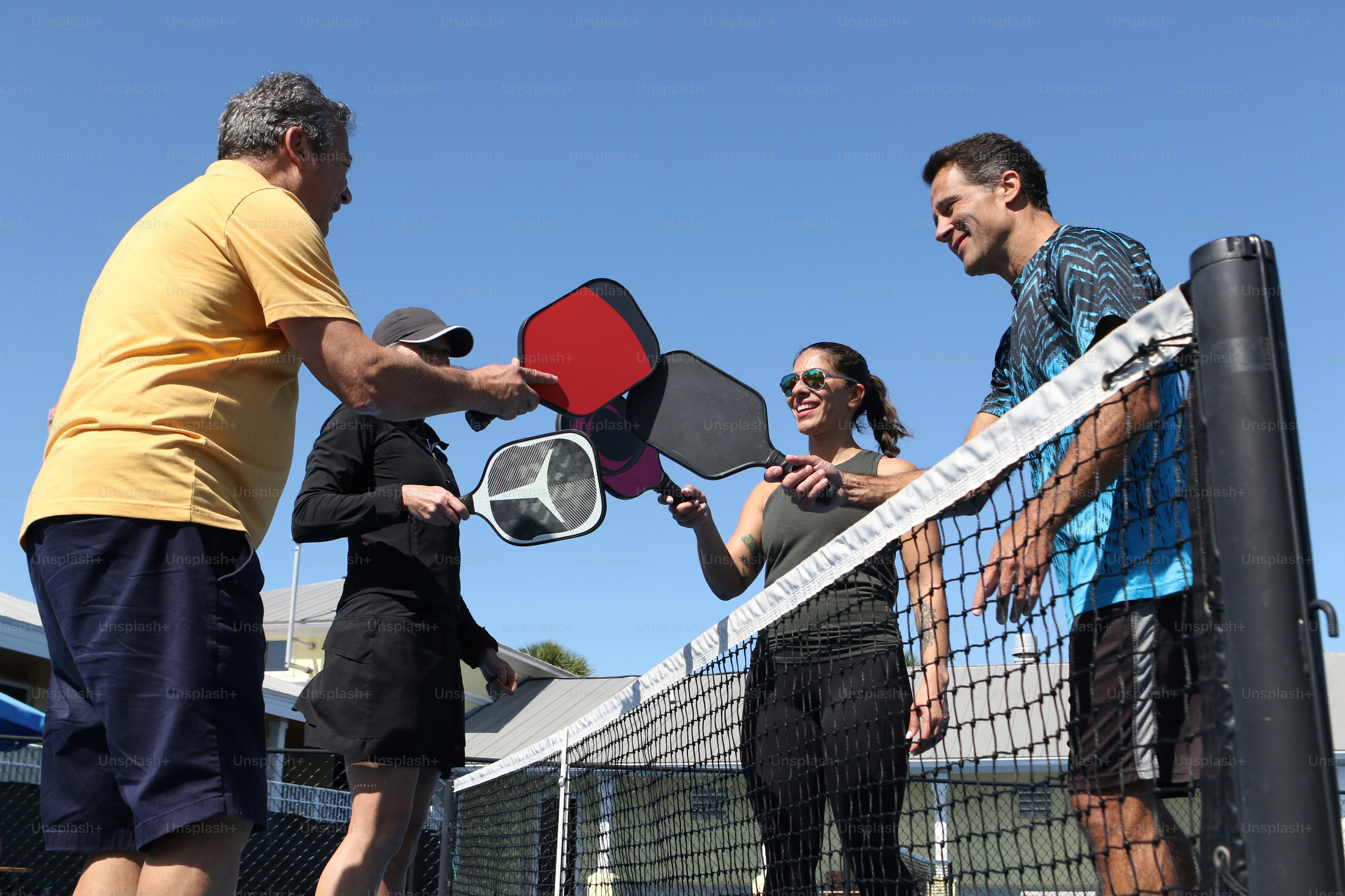 a group of people standing on a tennis court holding racquets