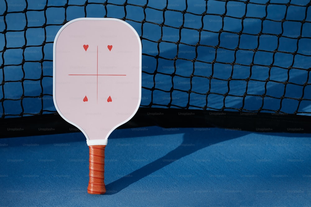a white paddle on a blue surface with a net in the background