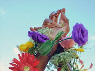 a person's hands holding flowers in front of a blue sky