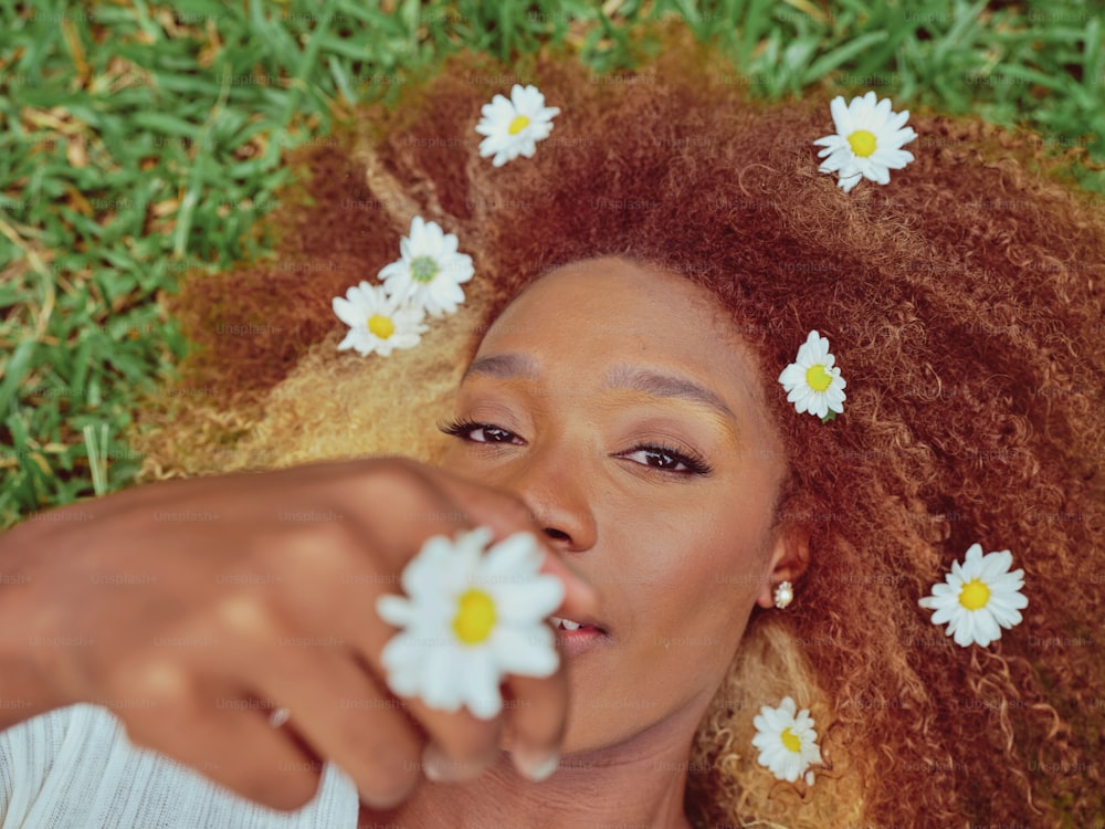 una donna sdraiata sull'erba con fiori tra i capelli