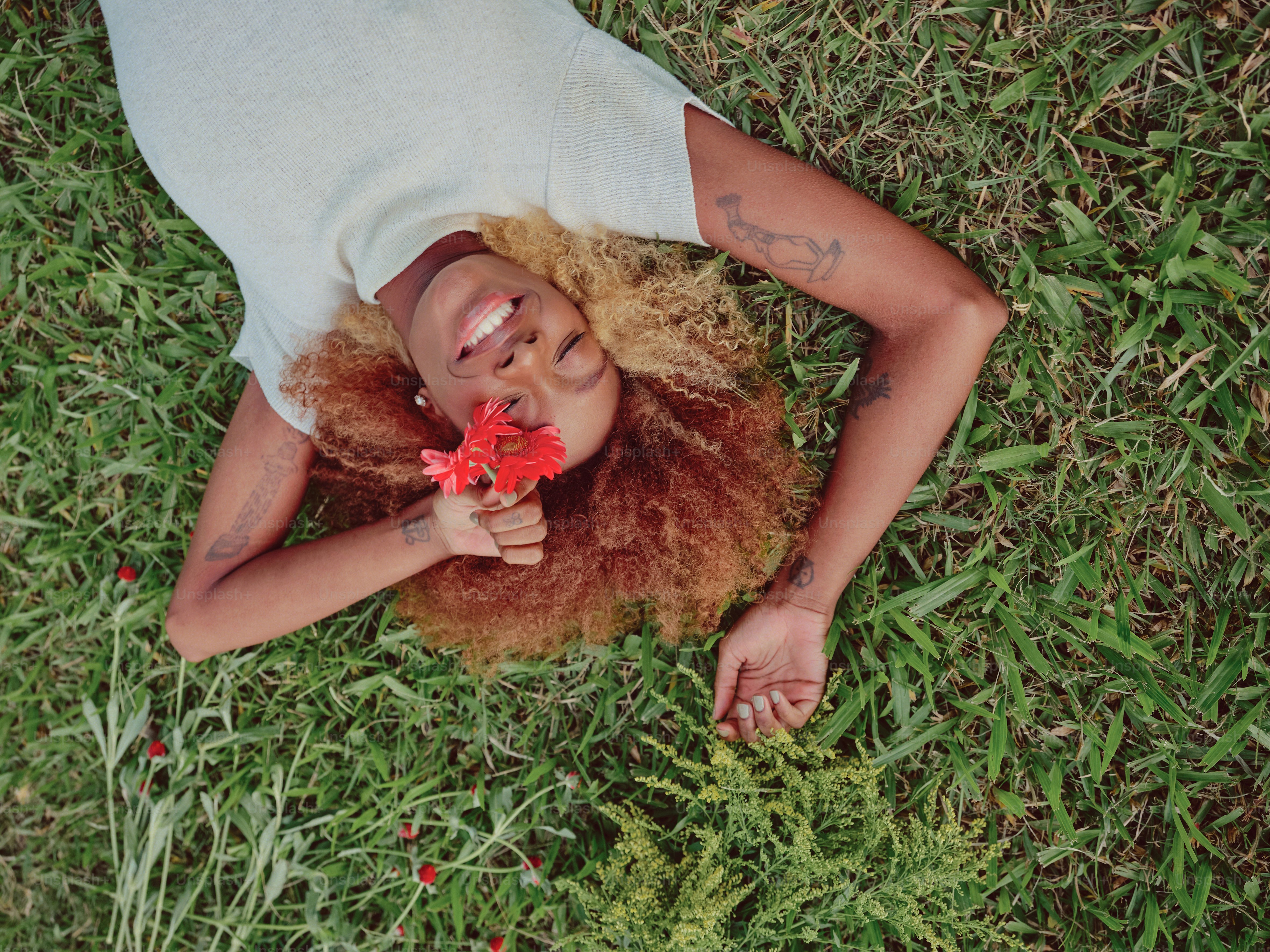 eine Frau, die mit einer Blume in der Hand im Gras liegt