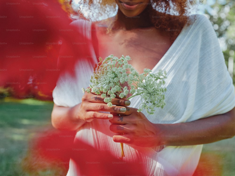 una mujer con un vestido blanco sosteniendo una planta