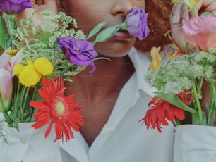 une femme tenant des fleurs devant son visage