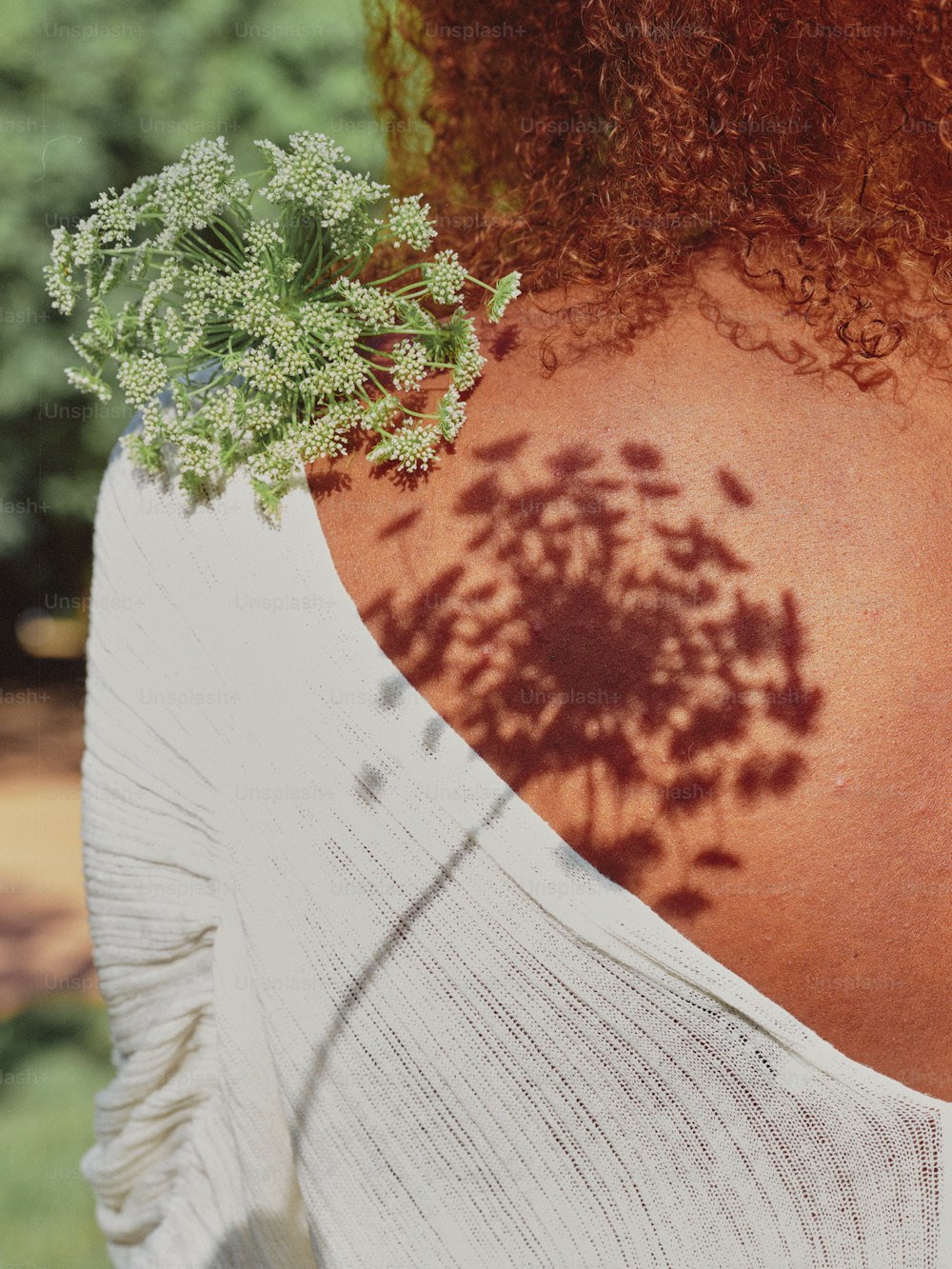 the back of a woman's neck with a plant growing out of it