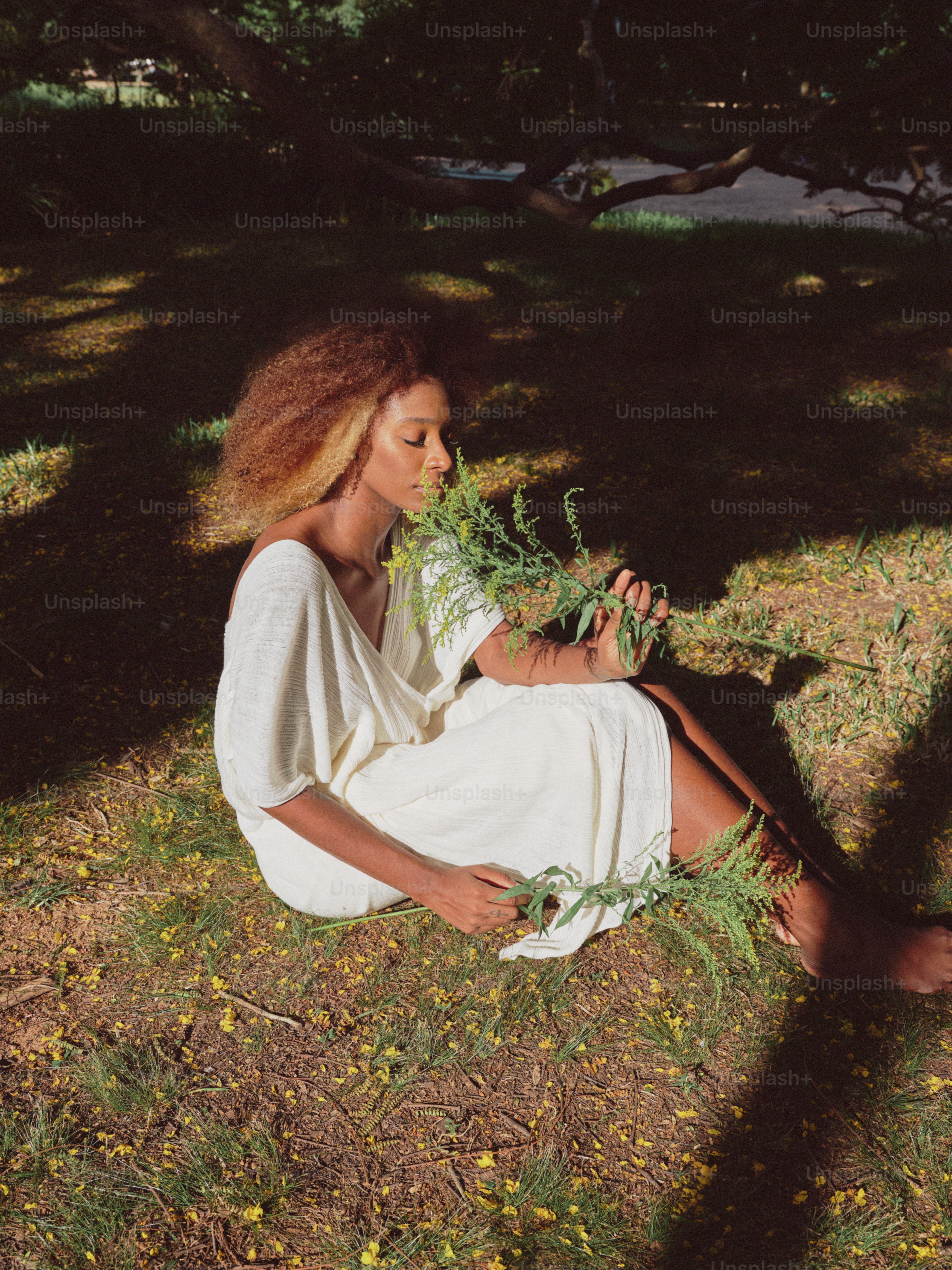 a woman in a white dress sitting in the grass