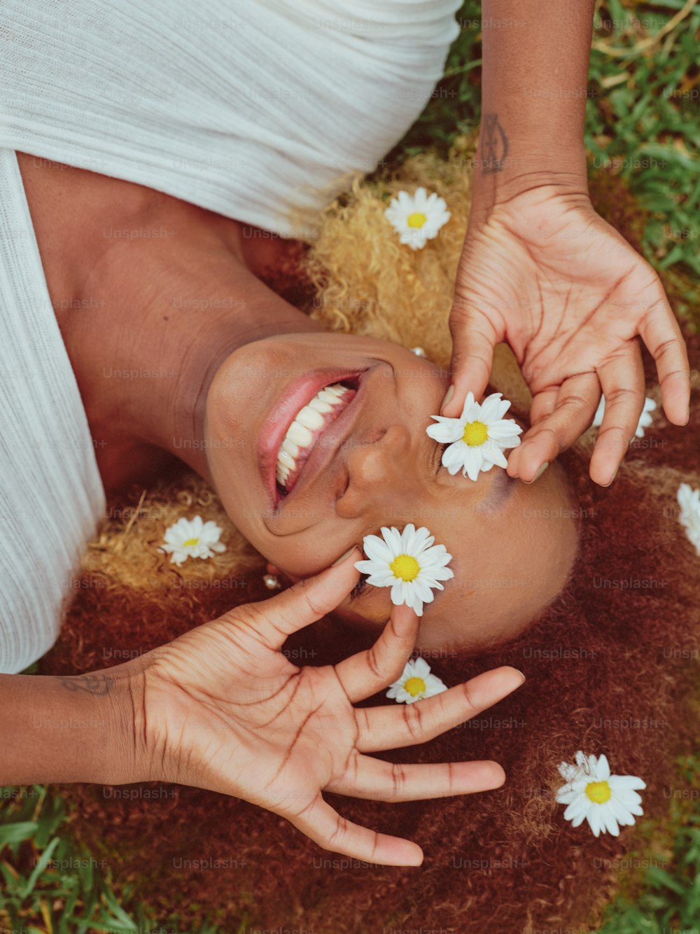 a woman laying on the ground with daisies in her hair