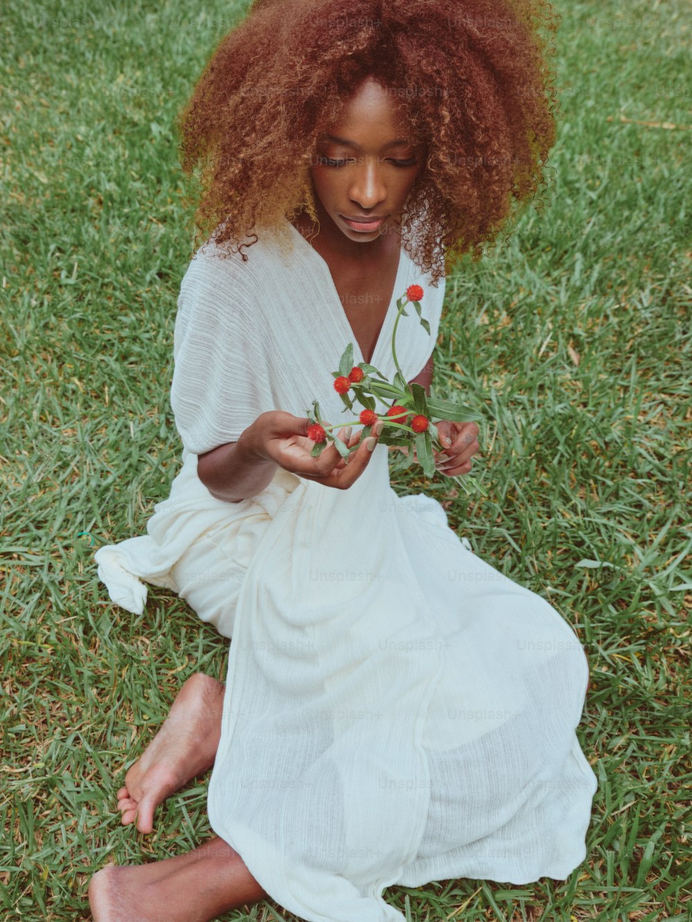 a woman sitting in the grass holding a flower