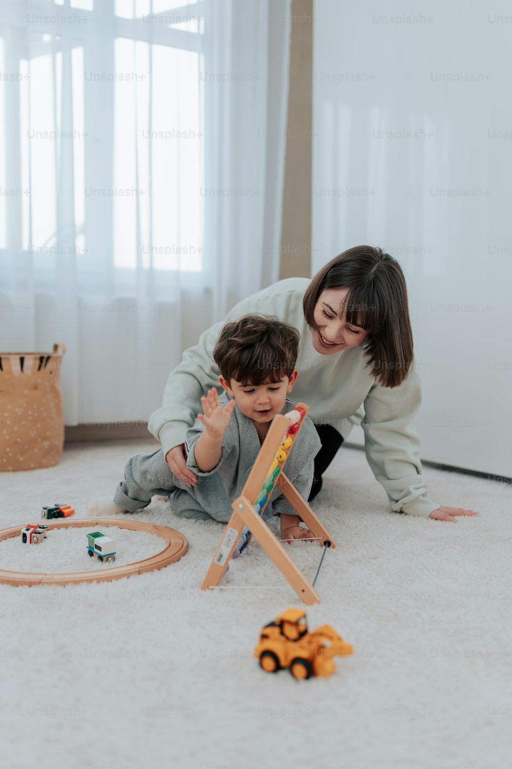 una donna e un bambino che giocano con giocattoli sul pavimento