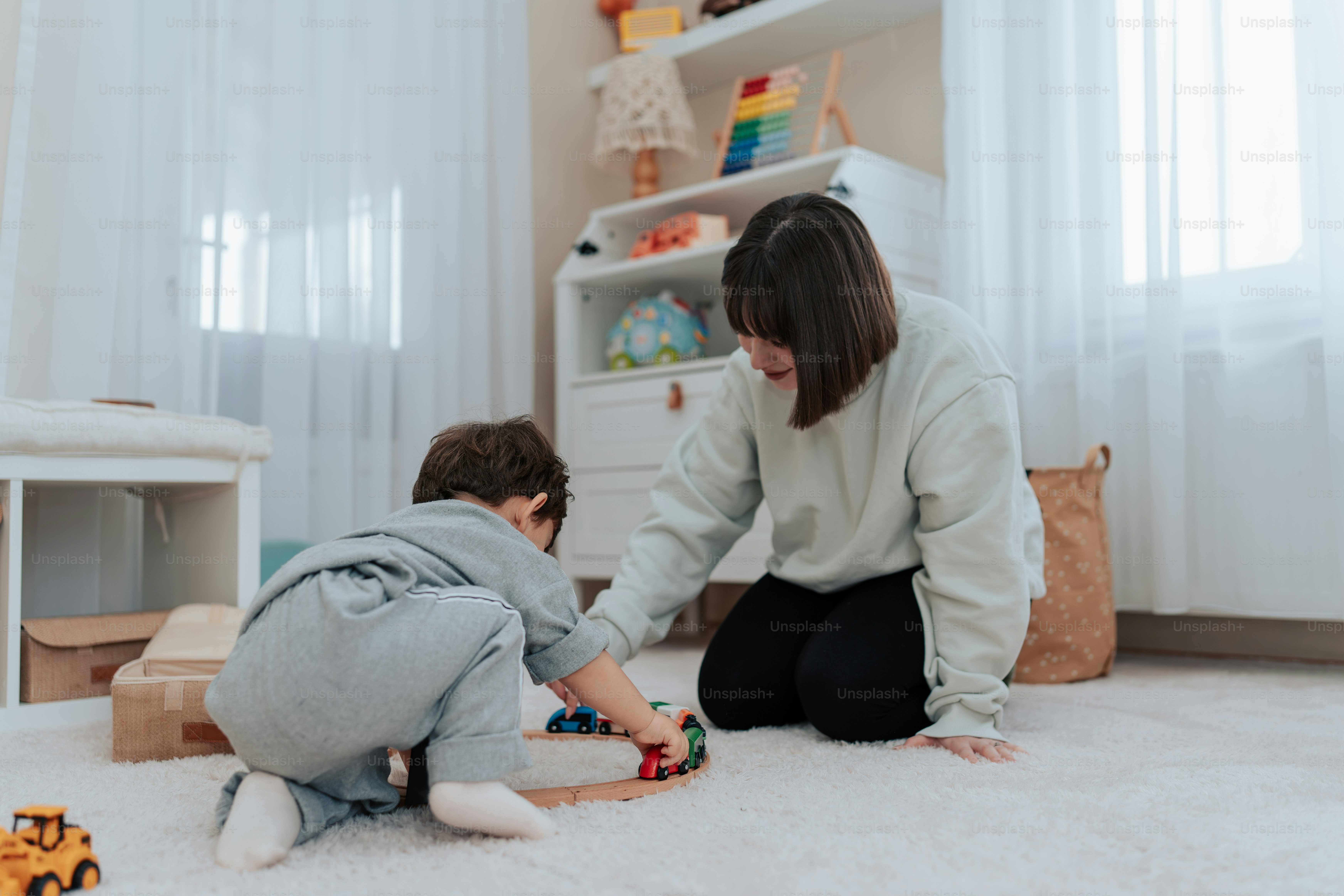 a woman kneeling down next to a child on the floor