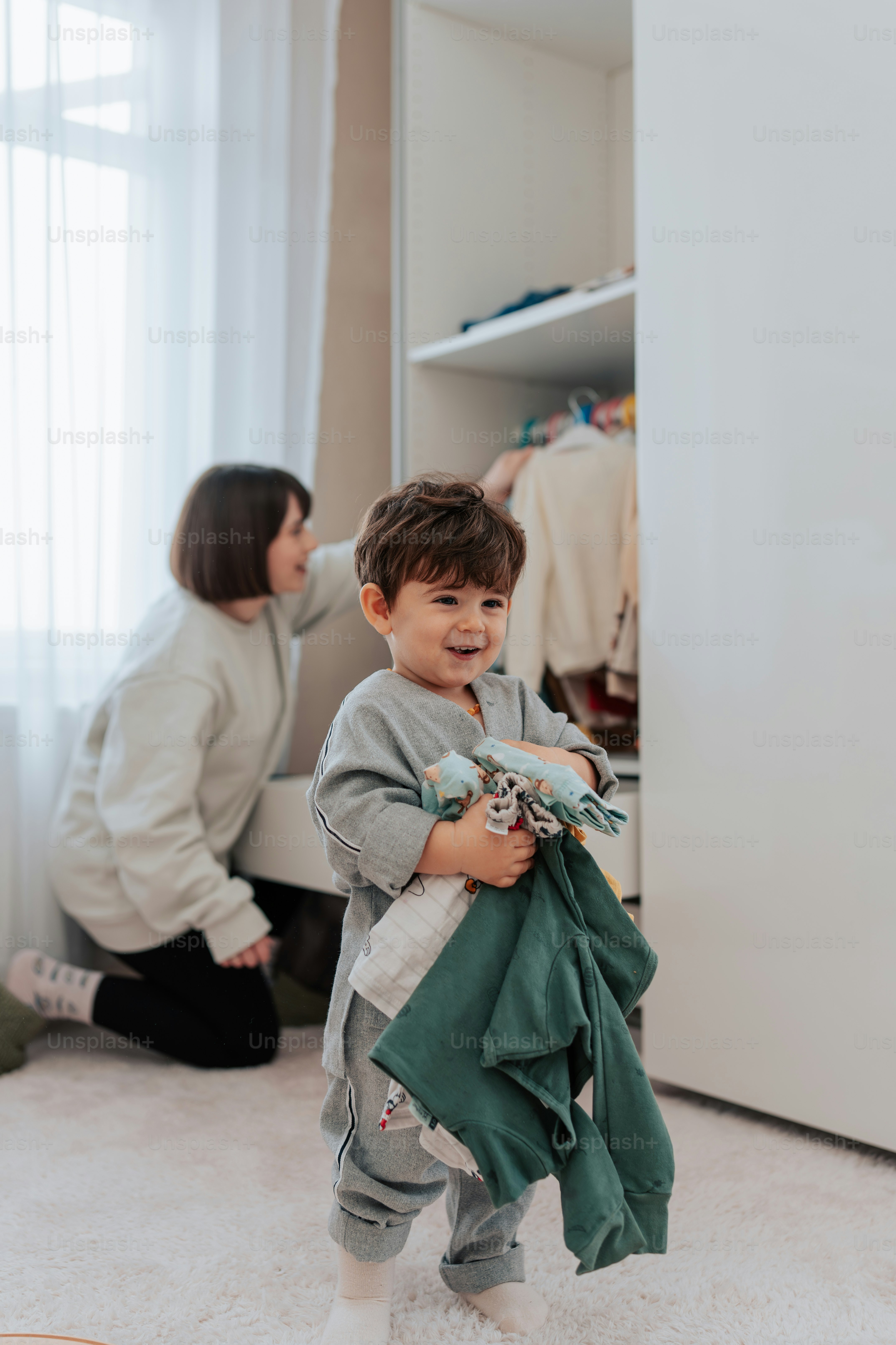 a little boy is holding a green jacket
