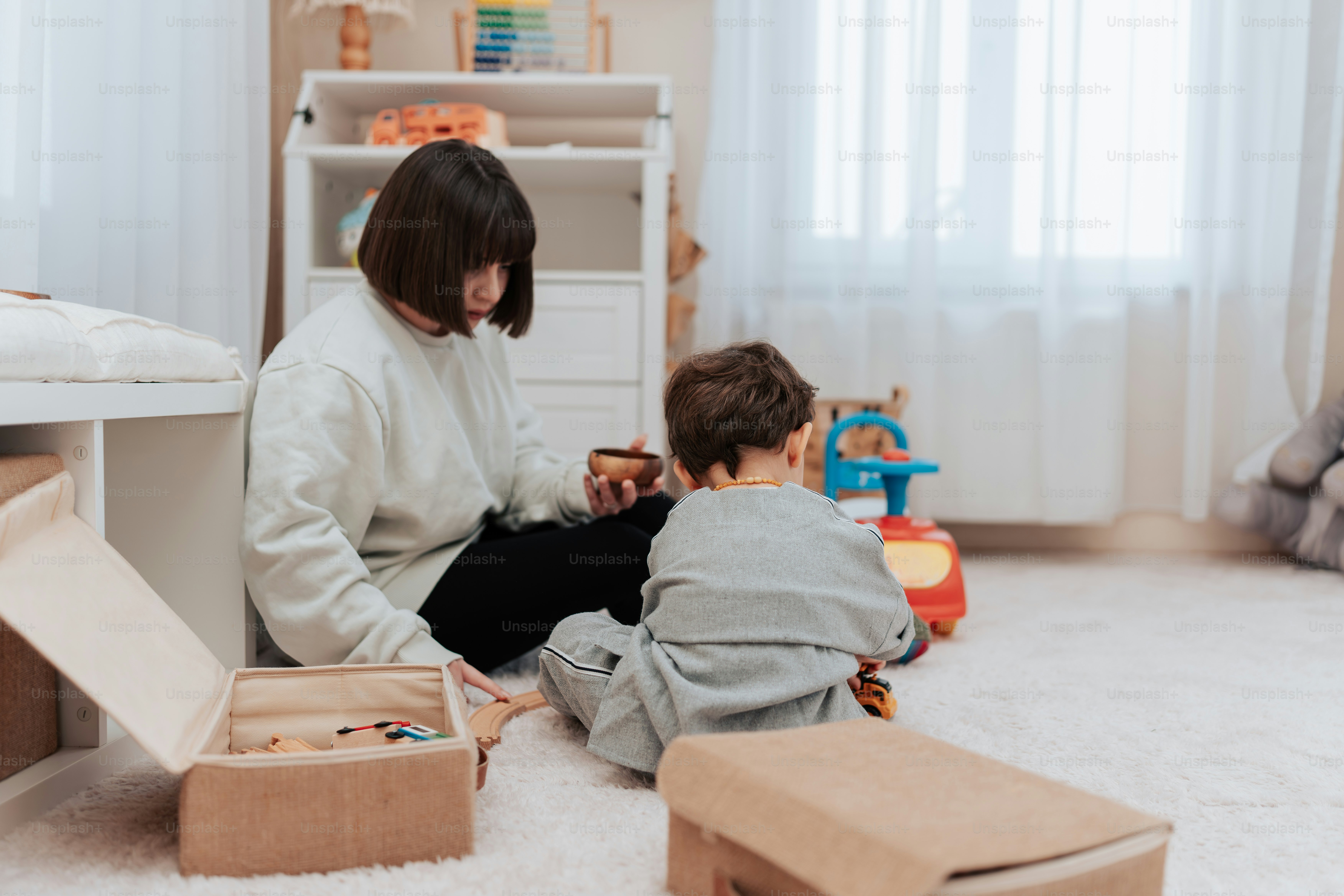 a woman sitting on the floor next to a child