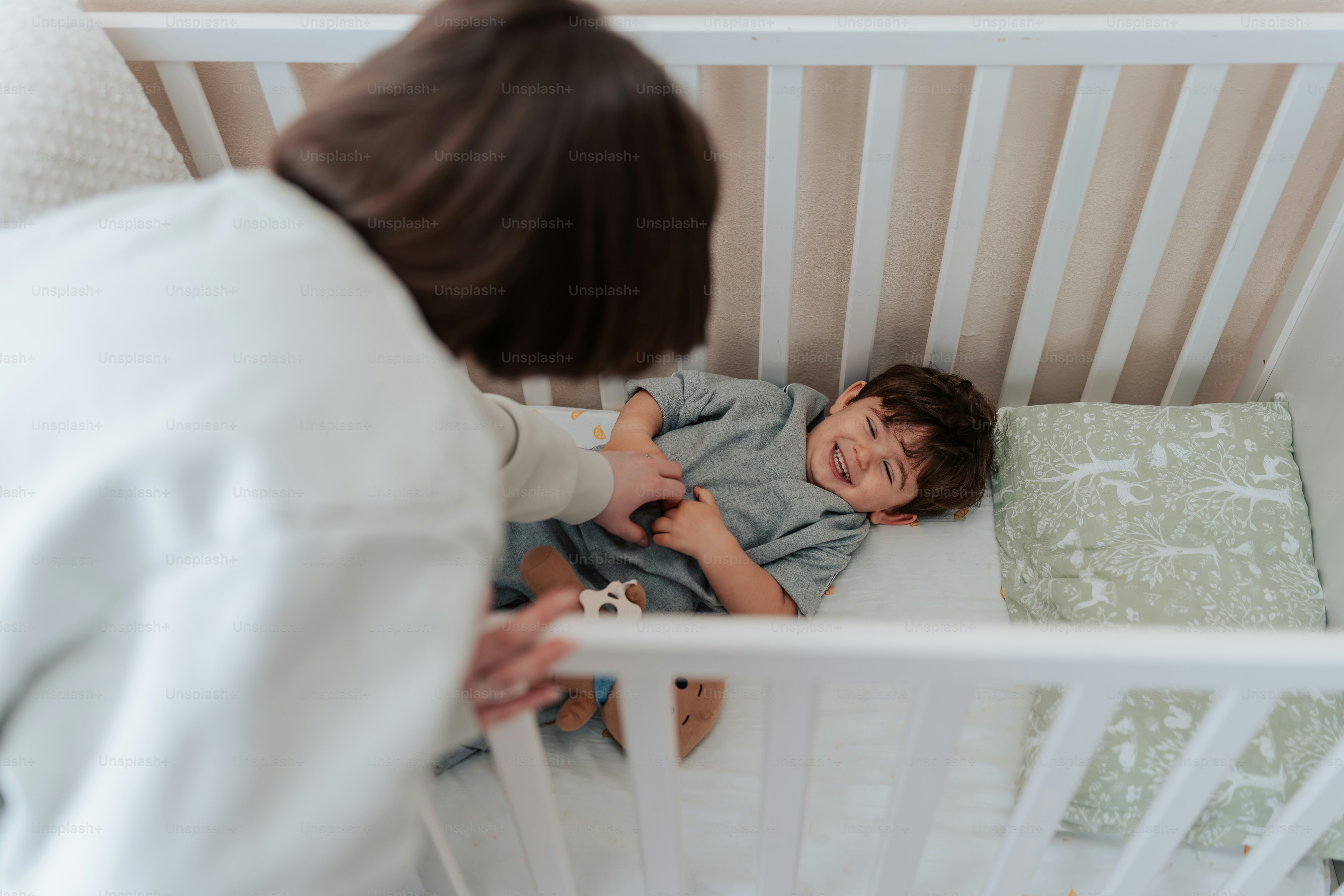 a little boy laying in a crib next to a woman