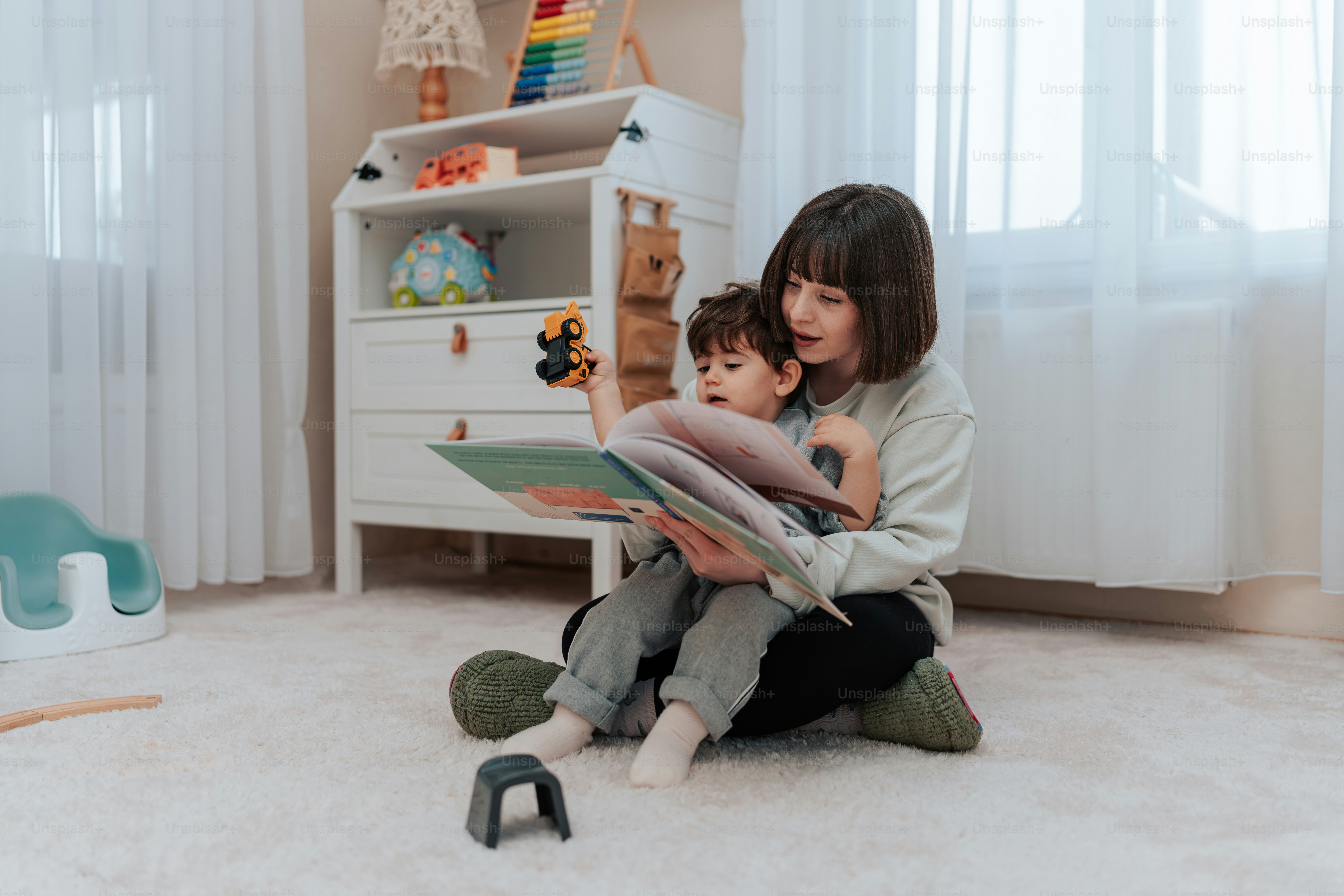 a woman sitting on the floor reading a book to a child