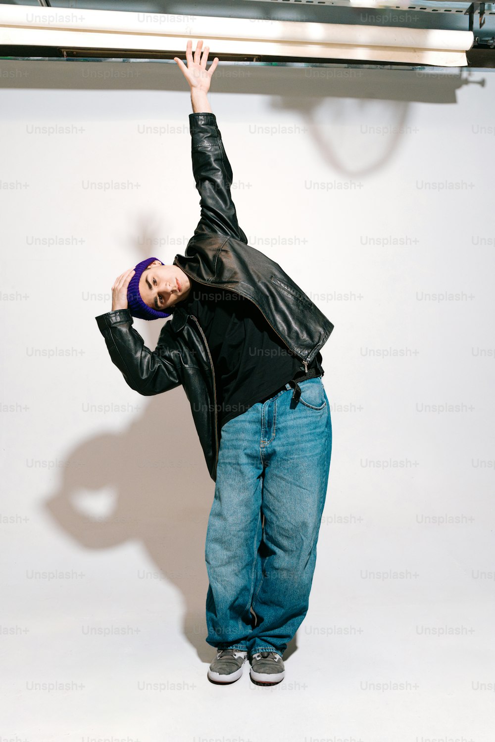 a man in jeans and a black jacket is holding his arms up